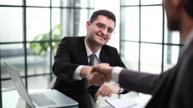 Neşeli genç müdürün yeni çalışanıyla tokalaşması portresi.