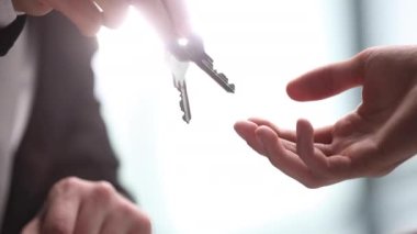 Dünya kiralama günü konsepti. Emlakçı anahtarları yeni sahibine veriyor. Elleri yakın çekim. Emlak kiralama ve satın alma