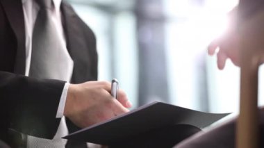 Yönetici konuşurken iş belgelerini ve kalemi tutuyor