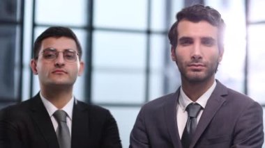 İki iş adamı ofiste el ele tutuşup el kol hareketi yapıyor.