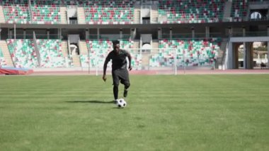 Afrikalı Amerikalı futbolcu futbol sahasında top oynuyor