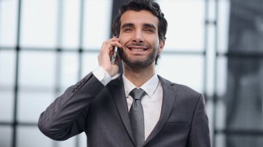 Takım elbiseli genç adam cep telefonuyla konuşuyor.