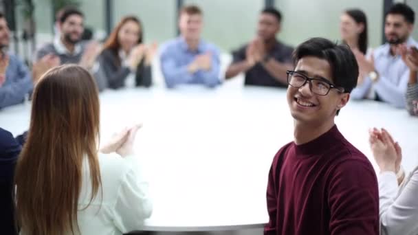 会議室での交渉カメラに眼鏡をかけたアジア系の若者がポーズをとって — ストック動画