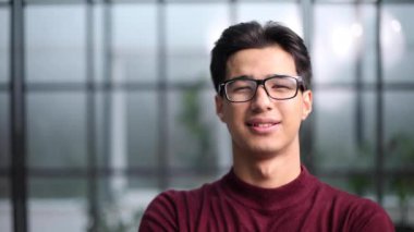 Kırmızı kazak içinde gülümseyen yakışıklı Asyalı genç adam.