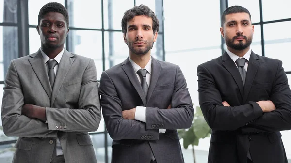 3人の同僚が腕を組んで近代的なオフィスのロビーに立ち — ストック写真