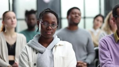 Başarılı bir Afrikalı Amerikalı yönetici meslektaşlarının önünde oturuyor.