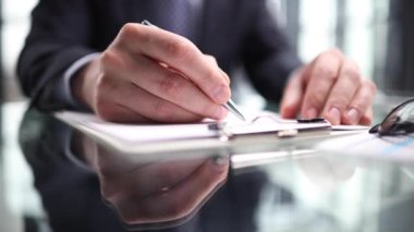 El, kağıt bir deftere notlar yazar, yakın plan.