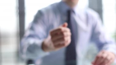 Beyaz gömlekli sıradan bir adam ofiste otururken hoş geldin jesti yapıyor.