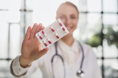 Farmakolojik terapi. Kadın doktor eczacının yakın plan portresi. Yeni etkili ilaç tedavisini sunan kameraya bakıyor. Sarı kapsüle odaklan. Kadın sağlık işçisi elinde.