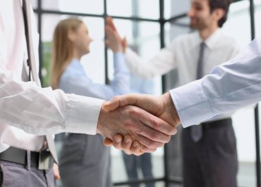 İş adamları el sıkışıyor. Şirket çalışma alanı koridorunda duran takım çalışması ortaklığı kuruyorlar.