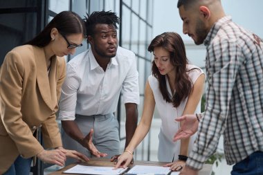 Group of young business people working together while standing in creative office