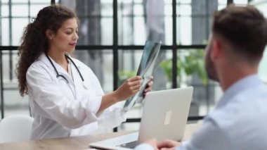 A female doctor and a patient at the reception are discussing an x-ray