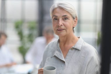 close-up mature woman holding a cup in the office.