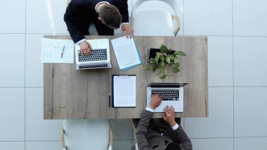 İki iş adamı bir sandalyede oturuyor ve dizüstü bilgisayardan bir şeyler izliyorlar.