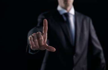 Odaklanmış iş adamı koyu arkaplanı işaret ediyor.