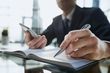 Kadının el ahşap masaüstü çeşitli öğeleri ile yerleştirilen sarmal Defteri'nde yazma yakın çekim