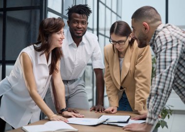 Ofiste masada dururken iş adamları mali tabloları tartışıyor.