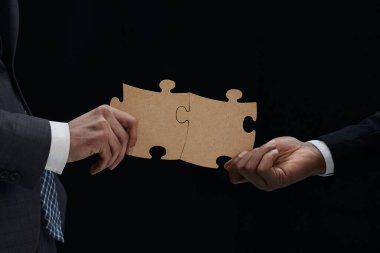 Birleşen iki beyaz Puzzle parçaları siyah arka plan üzerine yakın çekim iş ortakları