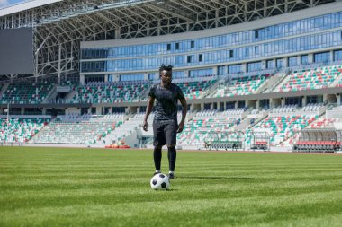 Stadyum sahasında futbol oynayan Afrikalı Amerikalı bir adam..