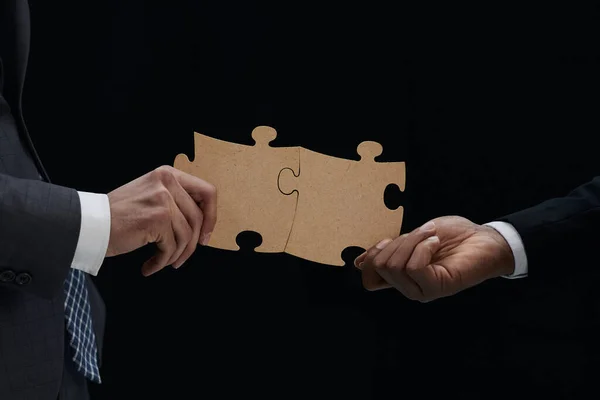 Close Van Business Partners Combineren Twee Witte Puzzelstukjes Zwarte Achtergrond — Stockfoto