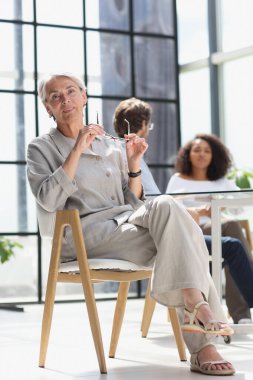 mature woman sitting with laptop looking at camera.