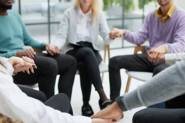 Grup terapisinde elele bir dairede oturan farklı insanlar