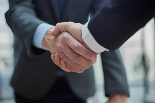 Ofis toplantısında iki farklı profesyonel iş adamı yönetici lider el sıkışıyor.