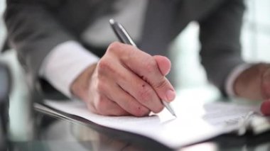 Ofis masasında oturan bir işadamı imzaya odaklı bir sözleşme imzalıyor..