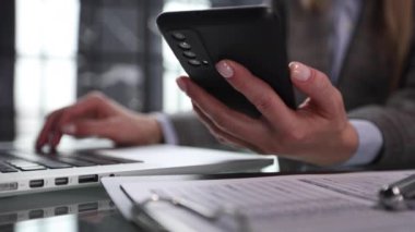 İş adamı ellerini ofis masasındaki cep telefonuyla meşgul ediyor.