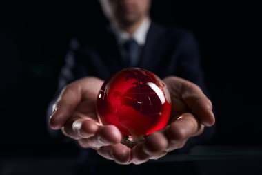 İş adamı elinde kıtalar olan cam küreyi tutuyor.