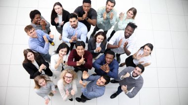 Tatmin olmuş çok ırklı şirket çalışanları modern ofiste birlikte duruyorlar..