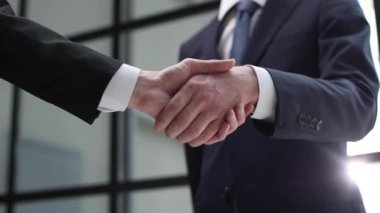 İş adamları ofis pencerelerinin önünde el sıkışıyor.