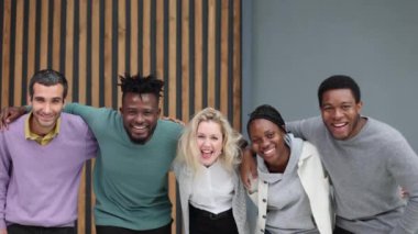 Ofiste dikilirken kameraya bakan çeşitli iş adamları.