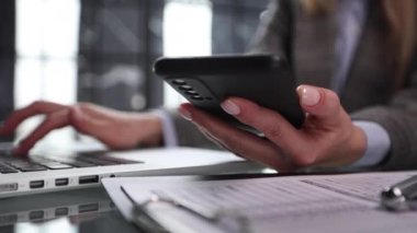 İş adamı ellerini ofis masasındaki cep telefonuyla meşgul ediyor.