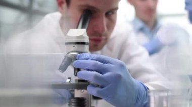 Genç bilim adamı bir laboratuvar mikroskop aramak. Biraz araştırma yaparak genç bilim adamı.