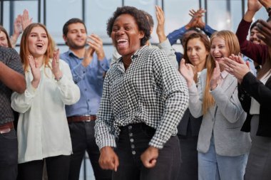 Gülümseyen çok ırklı meslektaşlar ofiste ortak iş başarısını veya zaferi kutluyorlar.