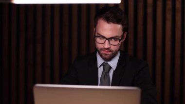 Modern bir ofisteki masasında bilgisayar kullanan genç bir iş adamının fotoğrafı..