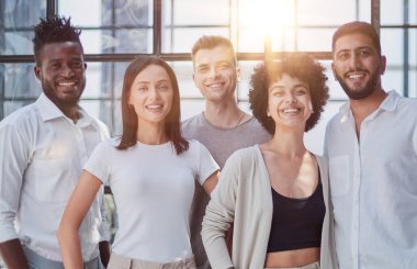 Başarılı yaratıcı iş ekibinin portresi kameraya bakıyor ve gülümsüyor. Başlangıçta çeşitli iş adamları bir arada duruyorlar.