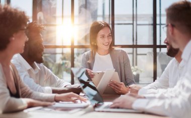 Çevrimiçi projeyi tartışan mutlu genç bayan çalışan, gözlüklü yetenekli takım liderine bilgisayar sunumu yapıyor. Uygulamaları kullanarak laptopta çift olarak çalışan dost canlısı meslektaşlar.