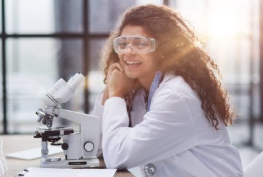 Biyolojik laboratuvarda genç bir kadın. Çekici genç bayan bilim adamları. Laboratuvarda mikroskop kullanan bir bilim adamı.