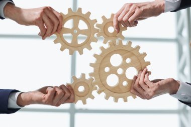 İnsanların elleri ofis çalışanlarının iş ortakları masadaki ahşap dişlilerin ortak resmini yapıyorlar.