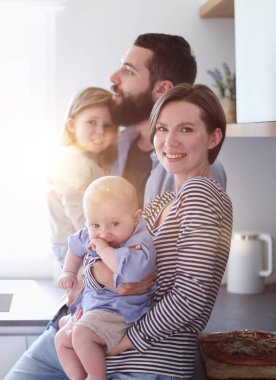 Family of 4 posing in the kitchen smiling and happy