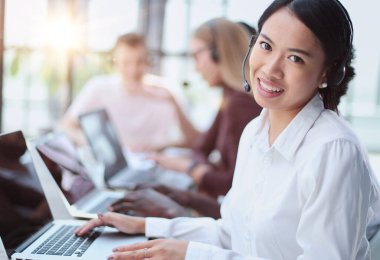 Genç Asyalı kameraman ofisteki kameraya bakıyor.