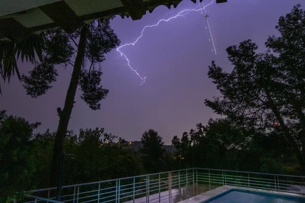 Lightning storm and wake of the passage of an airplane over a landscape in front of a swimming pool. long exposure photography