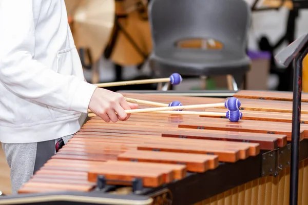 Musician hands with four drumsticks playing a marimba