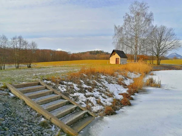 a staircase of the breeding pond in winter time, a small house