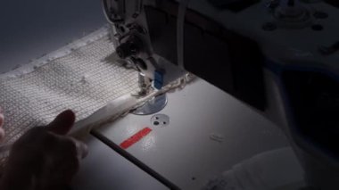 Dikiş makinesinin iğnesinin yavaş çekimde yakın çekimi. Dikiş atölyesinde terzi gri kumaş dikiyor. Kumaşı dikme süreci. Yüksek kalite 4K görüntü