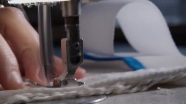 Dikiş makinesinin iğnesinin yavaş çekimde yakın çekimi. Dikiş atölyesinde terzi gri kumaş dikiyor. Kumaşı dikme süreci. Yüksek kalite 4K görüntü