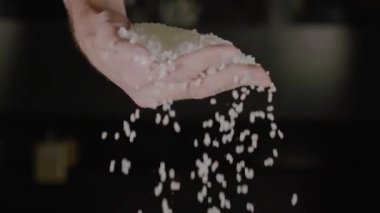 Koyu bir arka planda Ellerden Düşen Çiğ Beyaz Pirinç. Yüksek kalite 4k görüntü