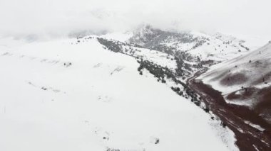 Mavi gökyüzü altında, kar dağı sıradağlarının hava manzarası. Dönüş yolu ve bulutların denizi. Arka planda 4k kış dronu görüntüleri. Yüksek kalite 4k görüntü